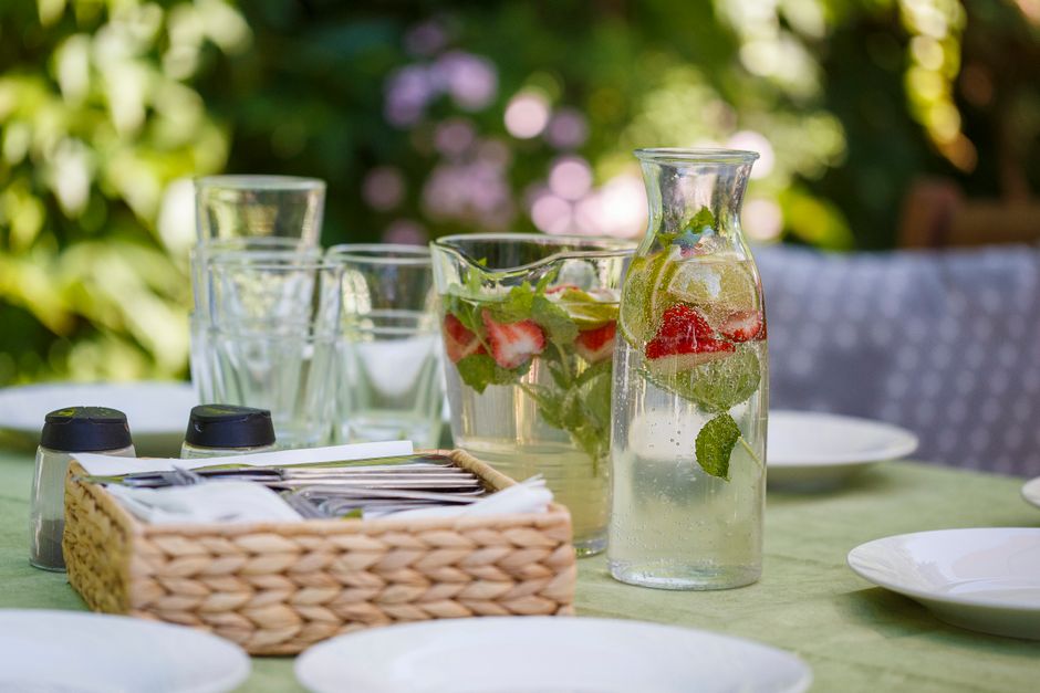 Set of water with lemon and strawberry composing with white plates and tools for eating food